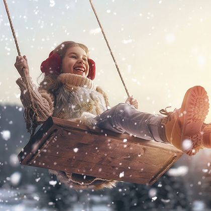 Kind schaukelt im Winter